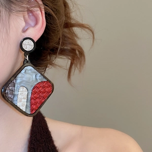 Detailed view of large geometric acrylic drop earrings in multicolored resin on a model