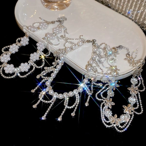 Detailed view of silver flower necklaces with radiant rhinestones and pearl tassels