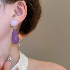 Detail of purple teardrop acrylic earrings worn by model for elegant style