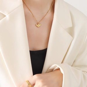 Gold wing pendant necklace and quilted pattern ring worn with an elegant white blazer
