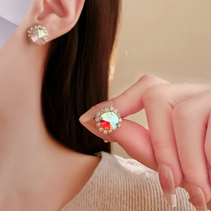 Macro detail of gold round earring with iridescent crystal and diamond halo on model