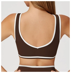 Détail du soutien-gorge de sport marron foncé avec bordures blanches et dos en U plongeant