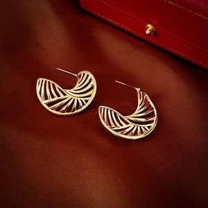 Detail of gold-plated heart tassel earrings with cutout design on brown silk fabric