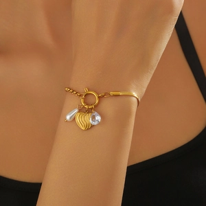 Gold stainless steel bracelet with heart charm, pearl, and rhinestone on model wrist