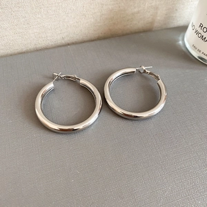 Close-up of polished silver hoop earrings on a textured display pad for daily wear