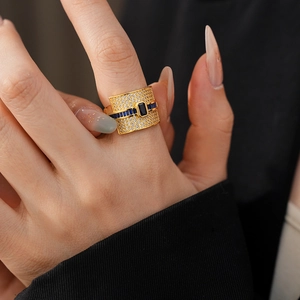 Close-up of gold plated ring with blue rectangular zircon stones and micro-paved crystals