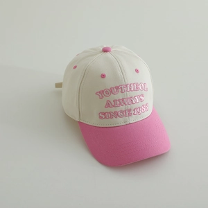 Detailed close-up of pink embroidered lettering on a beige and pink kids' baseball cap
