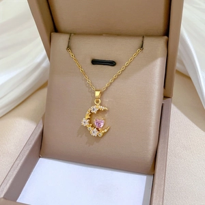 Detail of gold crescent moon necklace with pink heart zircon and starry white stones