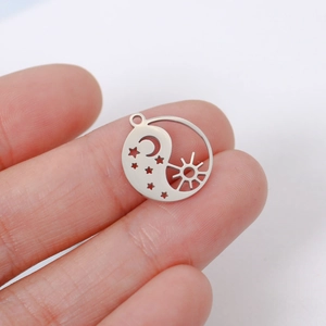 Macro detail of silver stainless steel Yin Yang pendant with sun moon and star cutouts
