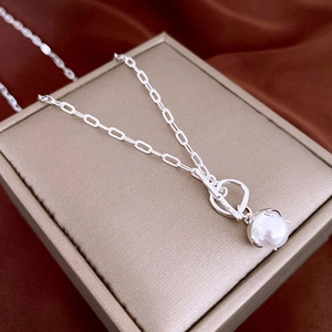 Detail view of silver chain necklace with pearl pendant and OT toggle clasp on jewelry box