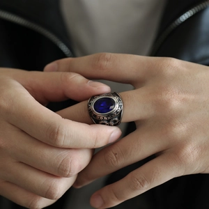Detalle de anillo punk con gran piedra azul ovalada y grabados de estilo industrial