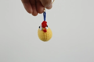 Close-up of handmade crochet yellow chicken keychain with detailed knit texture and ring
