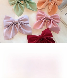 Flat lay of colorful handmade satin bow hair clips in pink, purple, and burgundy hues
