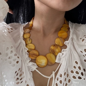 Close-up of bohemian gradient amber beads on a model wearing white lace clothing
