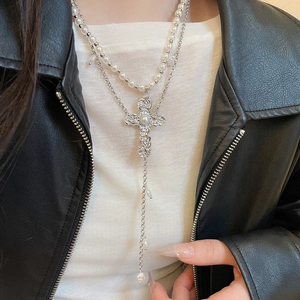 Détail du collier double rang avec croix argentée et perles sur mannequin en cuir noir