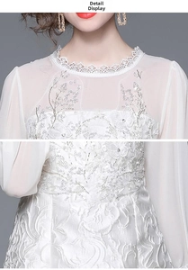 Close-up of white tweed dress featuring delicate floral lace embroidery and sequin details