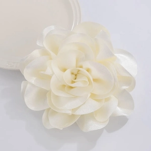 Detailed close-up of a white fabric camellia flower with silky multilayered petals
