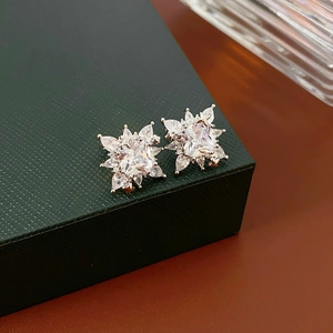 Gros plan d'un ear cuff fleur en argent serti de zircons posé sur un coffret à bijoux vert