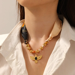 Detailed view of a gold bird pendant with black onyx worn on a silk ribbon chain
