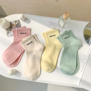 Detail of multi-color cotton socks with SMILE embroidery laid on a white surface