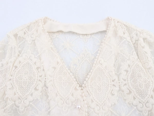 Dettaglio del top in pizzo con scollo a V, trame floreali traforate e bottone di perla