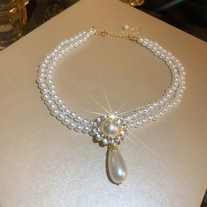 Detail of double-layer pearl necklace with rhinestone flower clasp and drop pendant