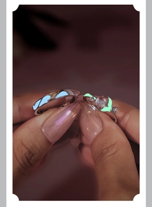 Close-up of luminous 925 silver couple rings with whale tail design glowing in blue-green