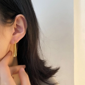 Gold stainless steel teardrop earrings with textured spiral design worn by a female model