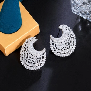 Macro shot of silver crescent earrings with sparkling cubic zirconia on a luxury stand