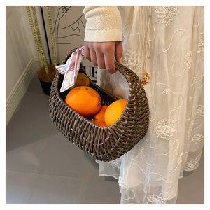 Detail of dark brown woven basket bag with floral silk scarf and oranges inside
