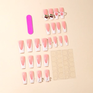 Detail of press-on nails set with cherry charms, heart pearls, and French tip designs