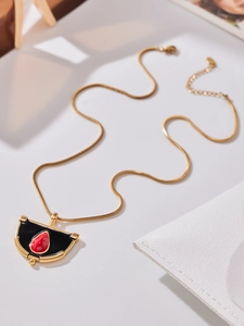 Vue détaillée du pendentif éventail doré avec émail noir et une pierre rouge en goutte