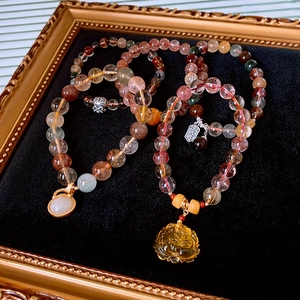 Detailed shot of multi-color rutilated quartz beads with carved lotus charms and silver tags