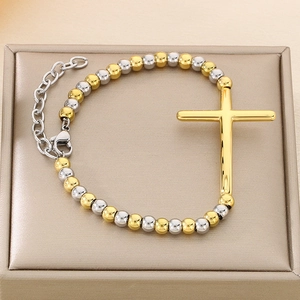 Detail of two-tone beaded stainless steel bracelet with a gold cross and lobster clasp