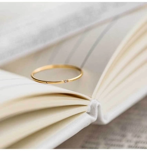 Macro shot of minimalist gold ring with a single zircon gem on white book pages