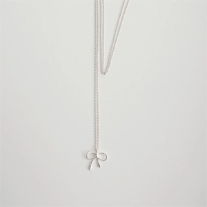 Macro shot of silver bow pendant featuring a twisted rope texture on a delicate chain