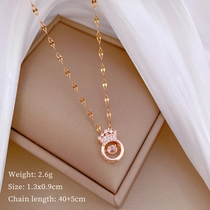 Detail view of rose gold crown pendant with sparkling stone on a beige gift box