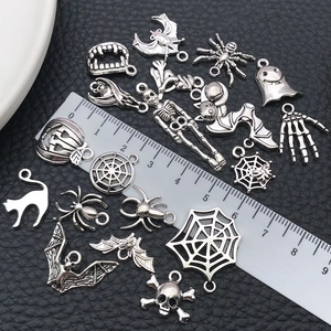 Silver Halloween charms assortment with skull and spider shapes next to a ruler