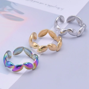 Macro detail of three adjustable leaf-shaped rings in silver, gold, and rainbow finishes