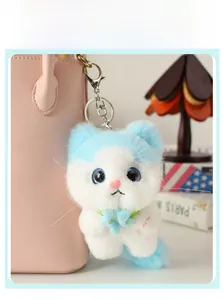 Detail of cute blue and white plush cat charm with metal clasp on a pink bag