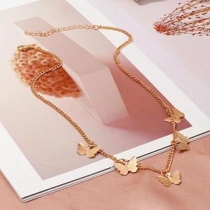Elegante collana dorata con cinque piccoli ciondoli a farfalla su sfondo rosa