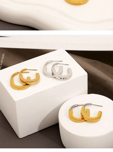 Detail of U-shaped gold and silver earrings displayed on white geometric stands