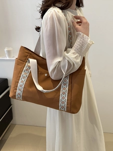 Borsa tote in tela marrone con tracolla con motivi etnici indossata sulla spalla da una modella