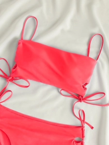 Detailed top view of bright pink bikini set with thin straps and side bow drawstring knots