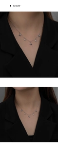 Detailed view of silver star and moon pendant necklace on black blazer model outfit