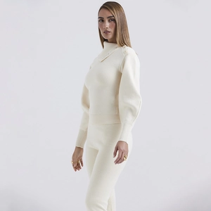 Detail of white rib-knit set showing lantern sleeves and button shoulder accents