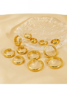 Macro view of polished 18K gold-plated titanium steel hoop earrings on silk