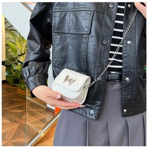 Detail shot of mini white butterfly bag with silver chain strap on black leather jacket