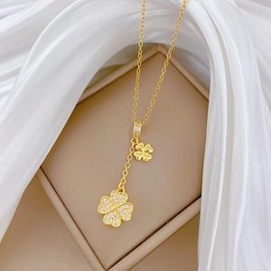 Macro detail of gold four-leaf clover pendant with glittering zircon inlay on silk