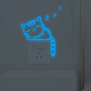 Luminous blue sleeping cat wall sticker glowing on socket panel in dark room
